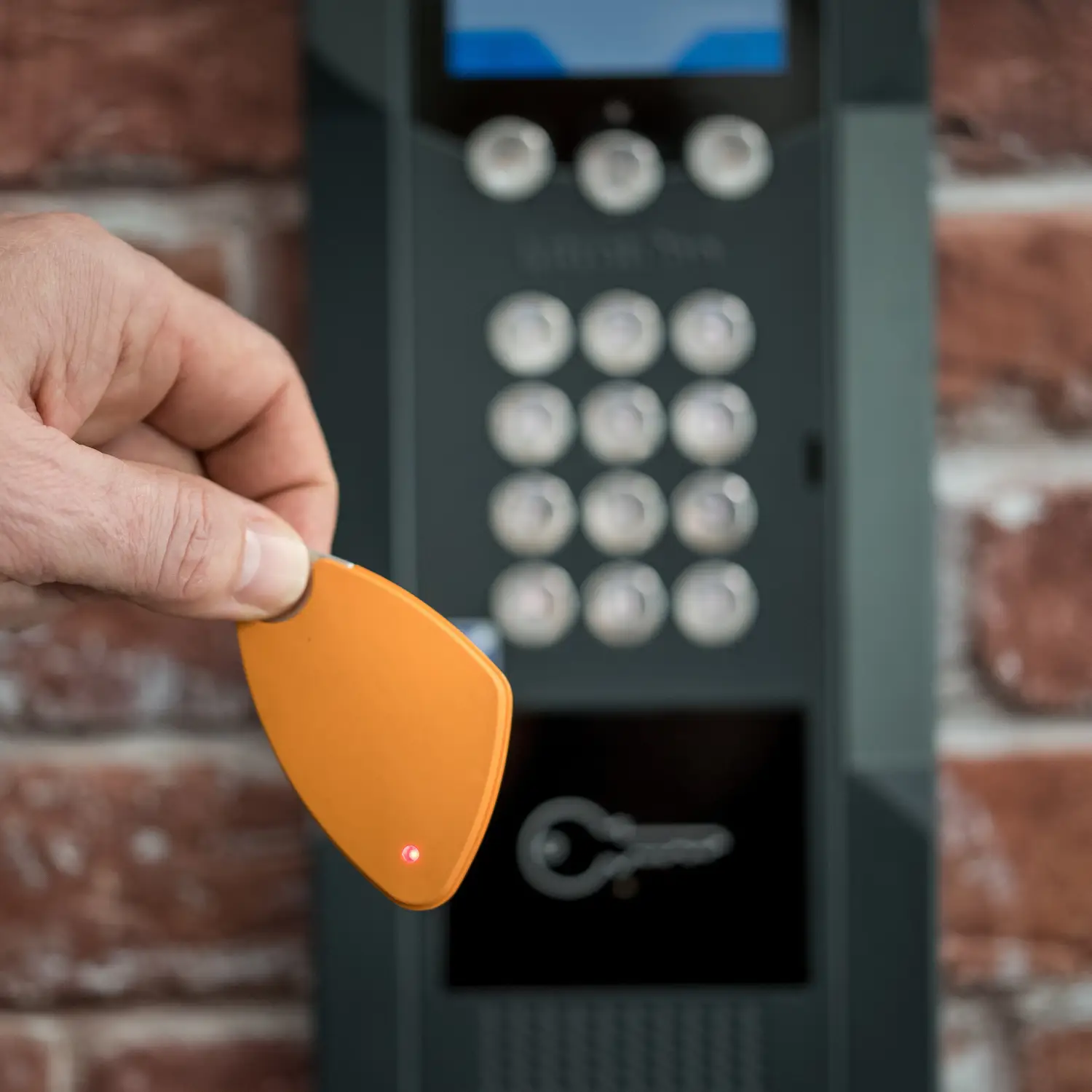 Badge Intratone orange approché d’un clavier d’accès sécurisé