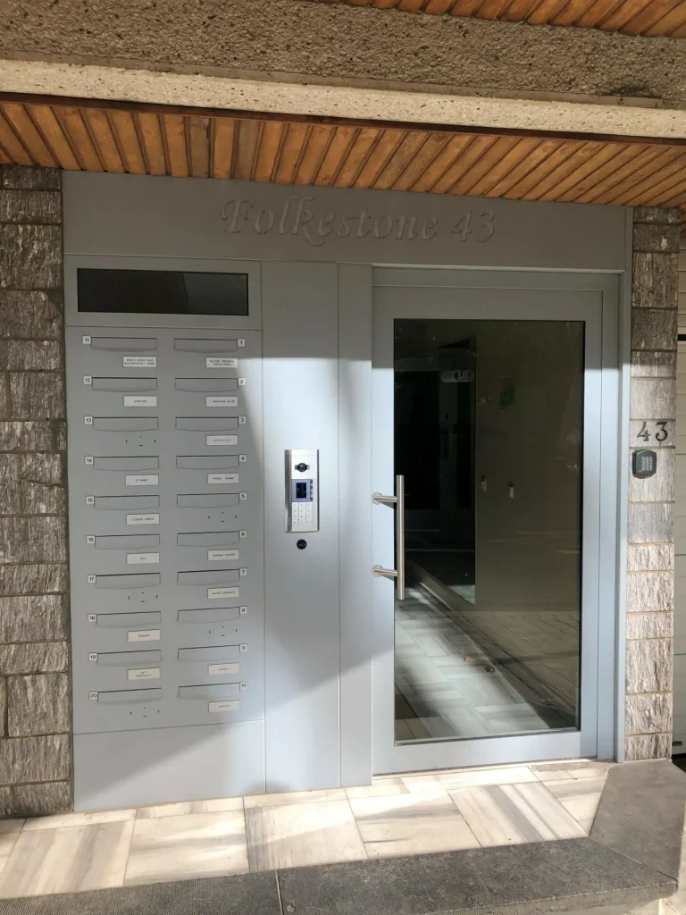 Porte d’entrée sécurisée grise avec boîtes aux lettres intégrées